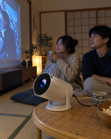 Illustrative Viremont setup: Couple watching movie on floor beside cylindrical projector